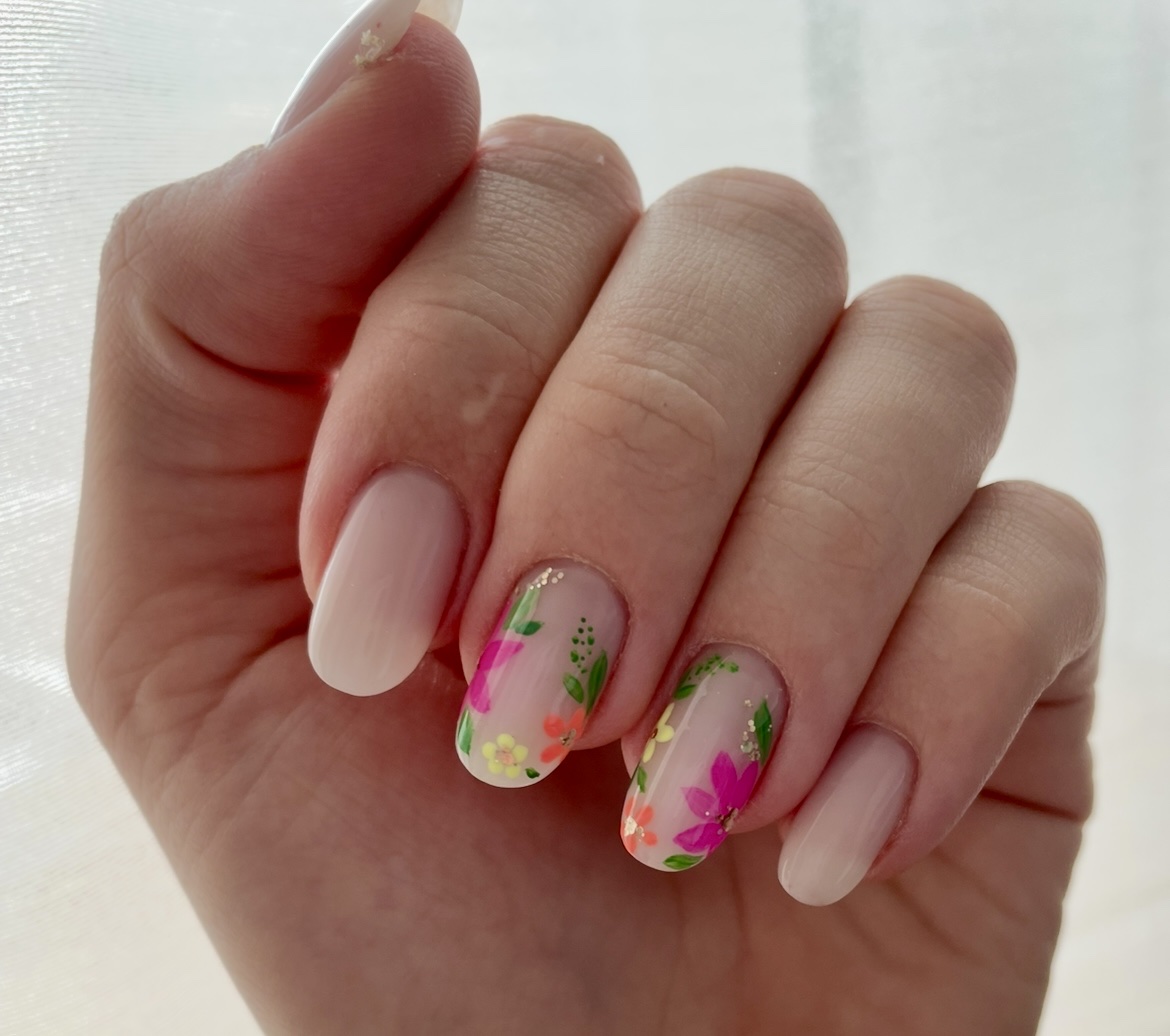 Nude nagels met twee accentnagels met roze en gele bloemen