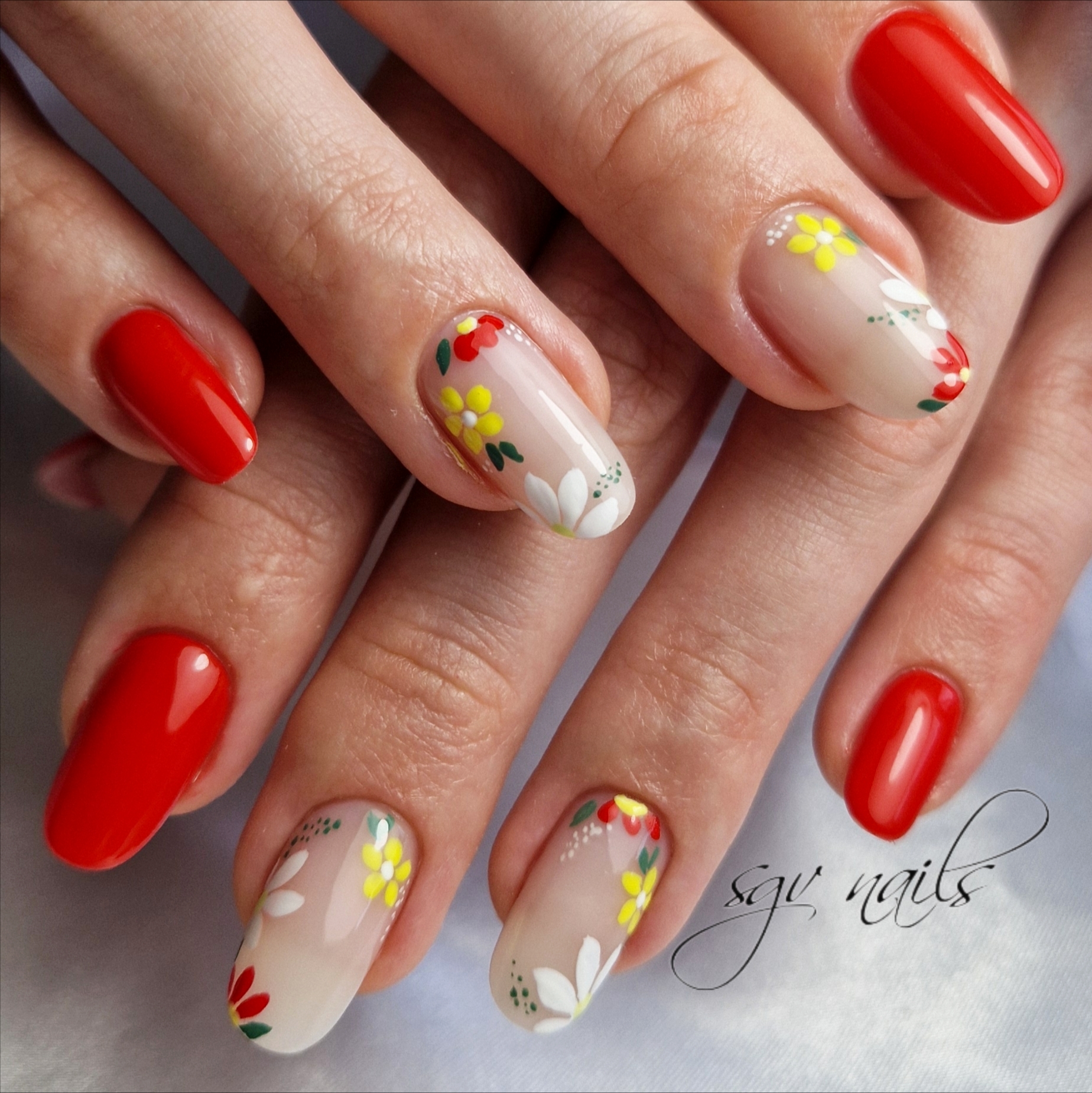 Rode nagels en nude nagels met rode, gele en witte bloemetjes